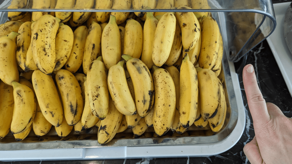 A close-up of a tray filled with ripe bananas, showcasing their yellow color and some with small dark spots, indicating ripeness.